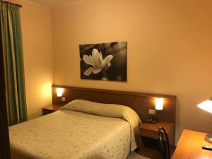 米兰帕拉迪索酒店的卧室配有一张床,墙上挂着一朵花