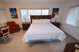 帕诺滩冲浪赛德度假酒店的卧室配有一张白色大床和一把椅子