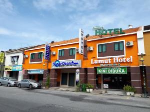 卢穆特Lumut Hotel的一座橙色的酒店,门前设有停车场