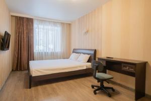 托木斯克Apartments Petrovskie on Kirova 39A的一间卧室配有一张床、一张桌子和一把椅子