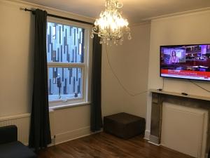 伦敦Residential Quarters, General Gordon Square的客厅配有平面电视和吊灯。