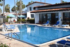 罗萨里托La Paloma Beach&Tennis Resort的一个带椅子的游泳池以及一座房子