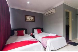 安邦Puteri Ampang Hotel的配有红色和白色床单的客房内的两张床