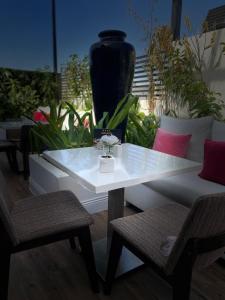 利雅德Dana Hotel & Residences的一张带两把椅子的白色桌子和黑色花瓶