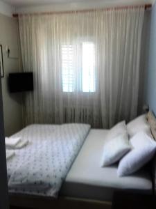 科托尔Pana-Eustahije 253的一间卧室配有一张带窗户和白色窗帘的床