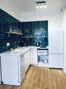 格但斯克Apartament z Widokiem na Morze的厨房配有白色家电和蓝色瓷砖