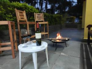 伊比乌纳Casa de Campo Lazer Completo Paraíso de Reservas Naturais em Sp的坐在火炉旁的桌子上,一瓶葡萄酒