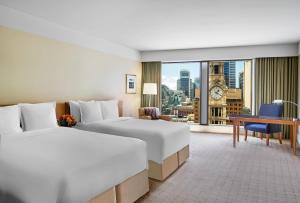 悉尼The Fullerton Hotel Sydney的酒店客房,设有两张床,享有城市美景。