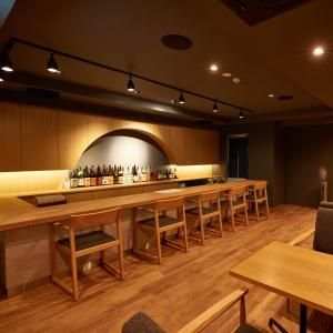 镰仓市KAMAKURA Hotel的餐厅内的酒吧配有木桌和椅子