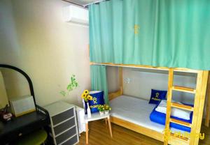 济州市甘德拉克旅舍的一间卧室配有一张带蓝色窗帘的双层床