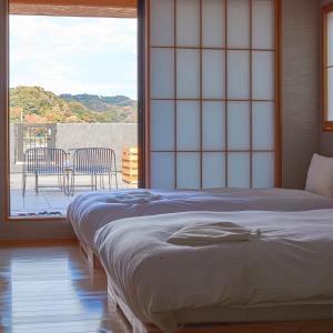 镰仓市KAMAKURA Hotel的一间卧室配有一张床,阳台配有椅子