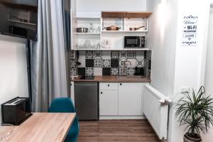 克拉约瓦Puzzle Apartaments&Studios的小厨房配有白色橱柜和桌子