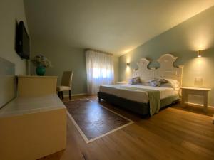 圣莱昂Hotel Foresteria Baglio Della Luna的一间卧室配有一张床、一张桌子和一台电视