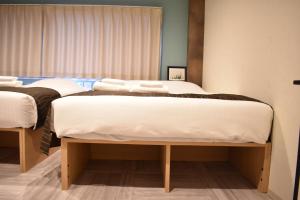 大阪Shinsaibashi House的配有白色床单的客房内的两张床