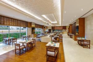 新德里新德里空港骄傲广场酒店的餐厅设有桌椅和沙发。