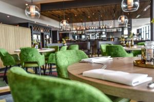 吕伐登Farm house Van der Valk Hotel Leeuwarden的餐厅设有木桌和绿色椅子