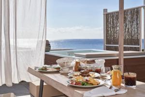 PaliochoriVolcano Luxury Suites Milos - Adults Only的阳台上摆放着食物盘的桌子