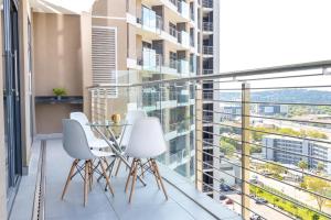 比勒陀利亚Menlyn Residence - 2 Bedroom Apartment的阳台配有白色椅子和玻璃桌