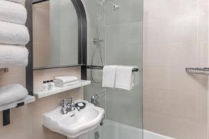 纽约voco The Franklin New York, an IHG Hotel的白色的浴室设有水槽和淋浴。