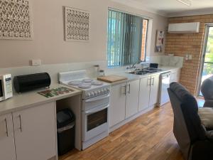科夫斯港Beachlander Self-Contained Holiday Apartments的厨房配有白色橱柜和炉灶烤箱。