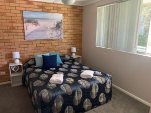科夫斯港Beachlander Self-Contained Holiday Apartments的一间卧室设有一张床和砖墙