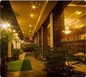 西里古里Rajdarbar Hotel & Banquet, Siliguri的一座带植物和灯光的庭院的建筑