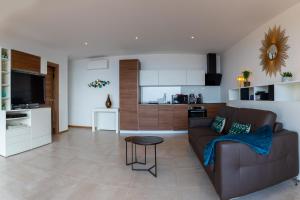 勒·雷约尔·卡纳德尔·苏尔Vistazur Luxueux appartement avec terrasse et piscine的一间带棕色沙发的客厅和一间厨房