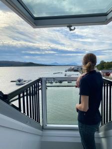 StonglandseidetSenja Fjordhotell and Apartments的站在一个眺望着水面的阳台上的女人
