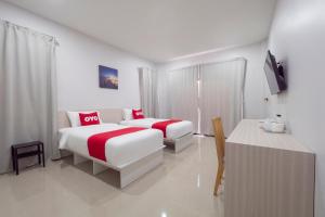 罗勇Capital O 75378 Thawapee Resort的酒店客房设有两张床和一张桌子。