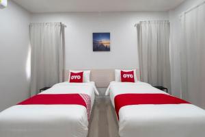 罗勇Capital O 75378 Thawapee Resort的两张位于酒店客房的床铺,配有红色枕头