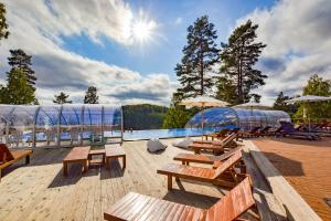 奥尔延Årjäng Camping & Stugor Sommarvik的甲板上配有长椅和遮阳伞的游泳池