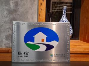 三星乡似禾苑民宿 Siheyuan Homestay的花瓶旁边的一个有房子的标志