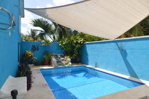 科苏梅尔拉斯安克拉斯别墅酒店的蓝色墙壁上的游泳池,带雨伞