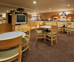 联合市Holiday Inn Express Hotel Union City San Jose, an IHG Hotel的一间带桌椅和电视的餐厅