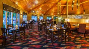 陶波陶波怀拉基度假酒店的餐厅设有木制天花板和桌椅