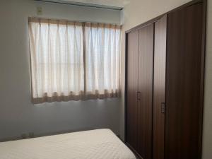 西条市Oyado Sukeya的一间卧室配有一张床、一个衣柜和一个窗户。