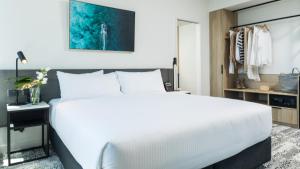 凯恩斯Oaks Cairns Hotel的卧室配有一张白色大床和一张书桌