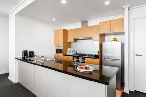 墨尔本探索南岸酒店的厨房配有白色橱柜和冰箱。