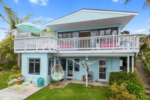 怀普Waipu Cove Palm Cottage - Waipu Cove Holiday Home的带阳台和甲板的蓝色房屋