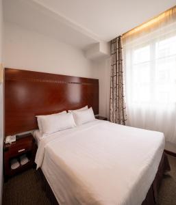 新加坡The Quay Hotel West Coast的一间卧室设有一张大床和一个窗户。