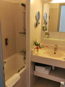 巴登戈维尼斯之家酒店的一间带水槽、浴缸和镜子的浴室