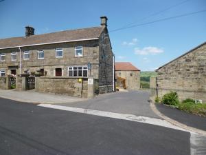 BradfieldPadley Farm的一座古老的石头建筑,前面有一条路