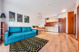 库瑞尼卡慕斯卡Apartamenty Sun & Snow Continental的一间带蓝色沙发的客厅和一间厨房