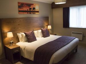 史云顿白鹿宾馆的酒店客房配有一张带紫色枕头的大床
