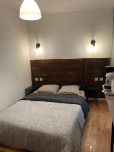 BeaumontBoms Appart的一间卧室配有一张大床和木制床头板