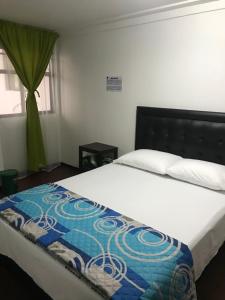 马尼萨莱斯Hostal El Eden Manizales的一间卧室配有一张带蓝白色毯子的床
