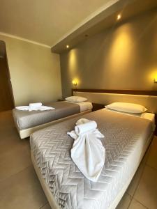 瓦西利基Cosmos Hotel的客房内的两张床和白色毛巾