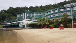 安格拉杜斯雷斯Angra dos Reis, Angra Inn, Cantinho perfeito的海滩上的酒店,配有椅子和遮阳伞