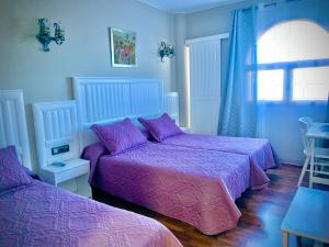 佩多拉卡斯蒂略博纳维亚酒店的一间卧室设有两张带紫色床单的床和窗户。