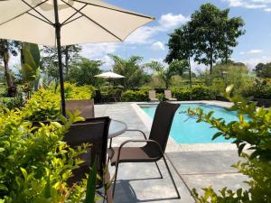 拉特瓦伊达Finca Hotel Brasilia的游泳池旁配有遮阳伞的桌椅
